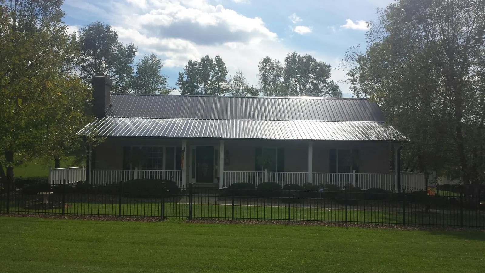 Gray metal roof on a brick ranch with a full width front porch — Gutter Guard Installation work by our crew in Gilman