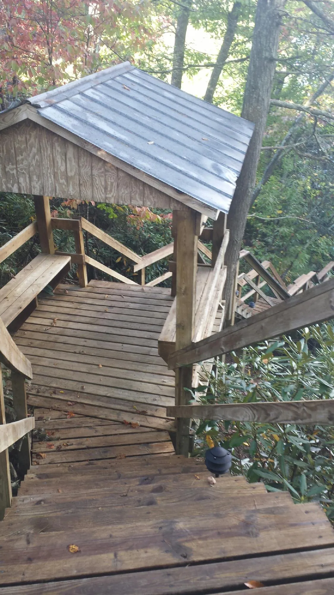 Metal roofed shelter over wooden steps on a wooded walkway — Skylight Repair & Installation work by our crew in Gilman